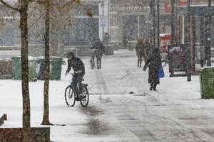 Winterse sneeuwval bedekt stadsstraat met fietsers