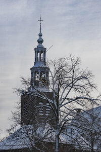 Sneeuwbedekte kerktoren tegen grijze winterlucht