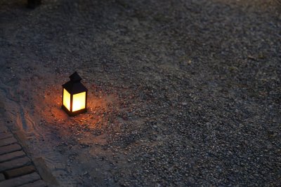 Lantern glowing softly on a gravel path during an evening gather