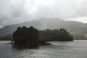 Mistig meer met eiland en bergachtergrond