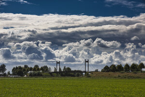 Wolken boven groen veld met brug in de verte