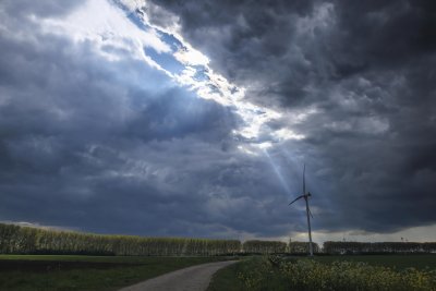 Dramatic cloud formation highlights wind turbine in rural landsc