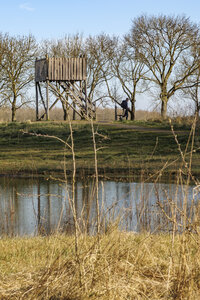 Viewing tower beside calm pond in rural landscape on a sunny day