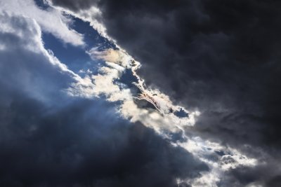 Dark storm clouds gather with a hint of sunlight breaking throug