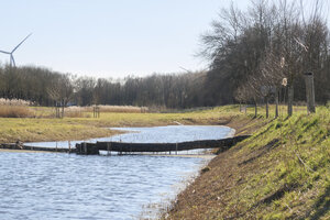 Scenic riverbank view with a wooden structure under a clear sky