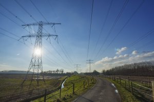 Hoogspanningslijnen in landelijk landschap onder blauwe lucht