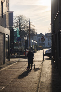 Elderly woman walking with walker in quiet city street during go