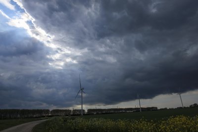 Dark clouds gather over a wind farm in a rural landscape during