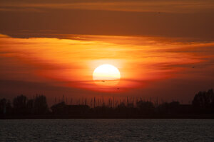 Levendige rode zonsondergang boven brede rivier