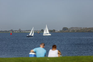 Stel kijkt naar zeilboten op kalm meer