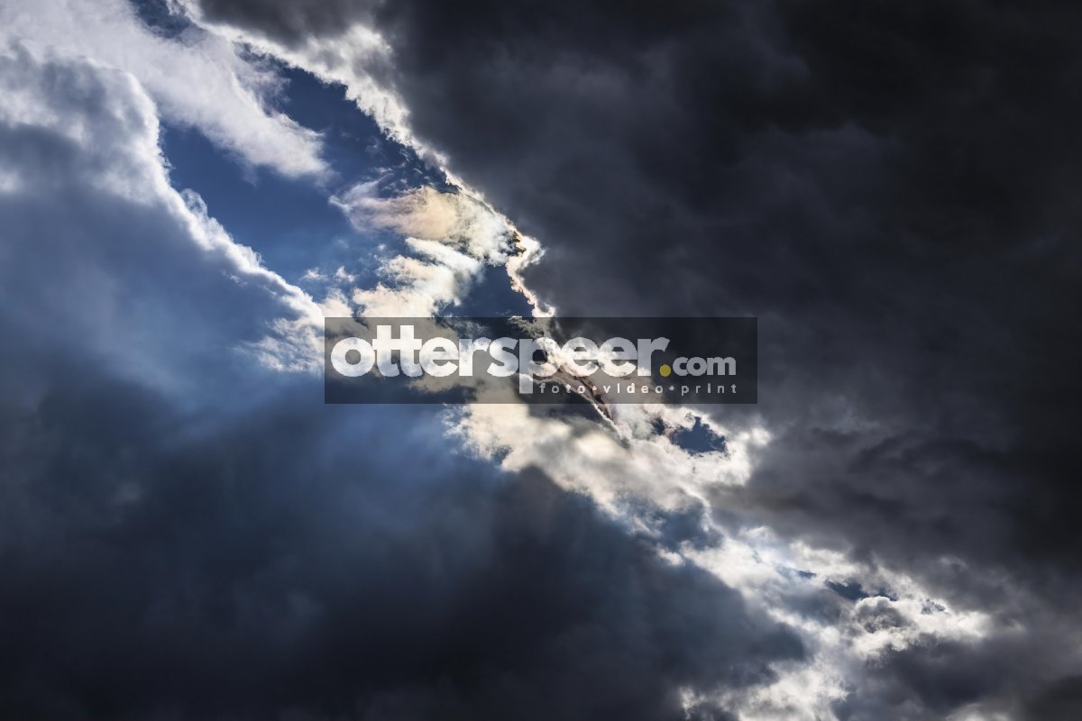 Dark storm clouds gather with a hint of sunlight breaking throug