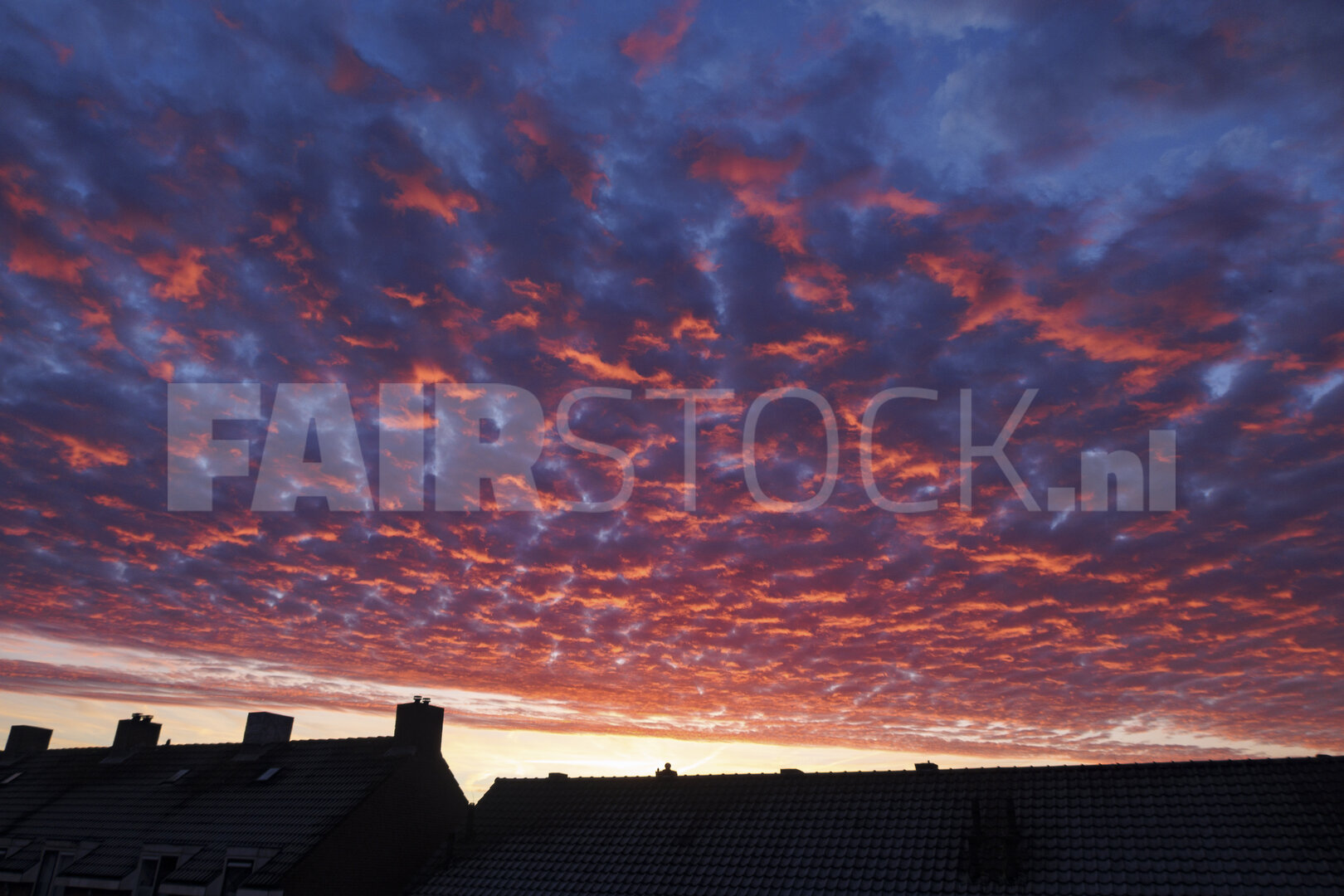 Adembenemende zonsondergang boven huisdaken