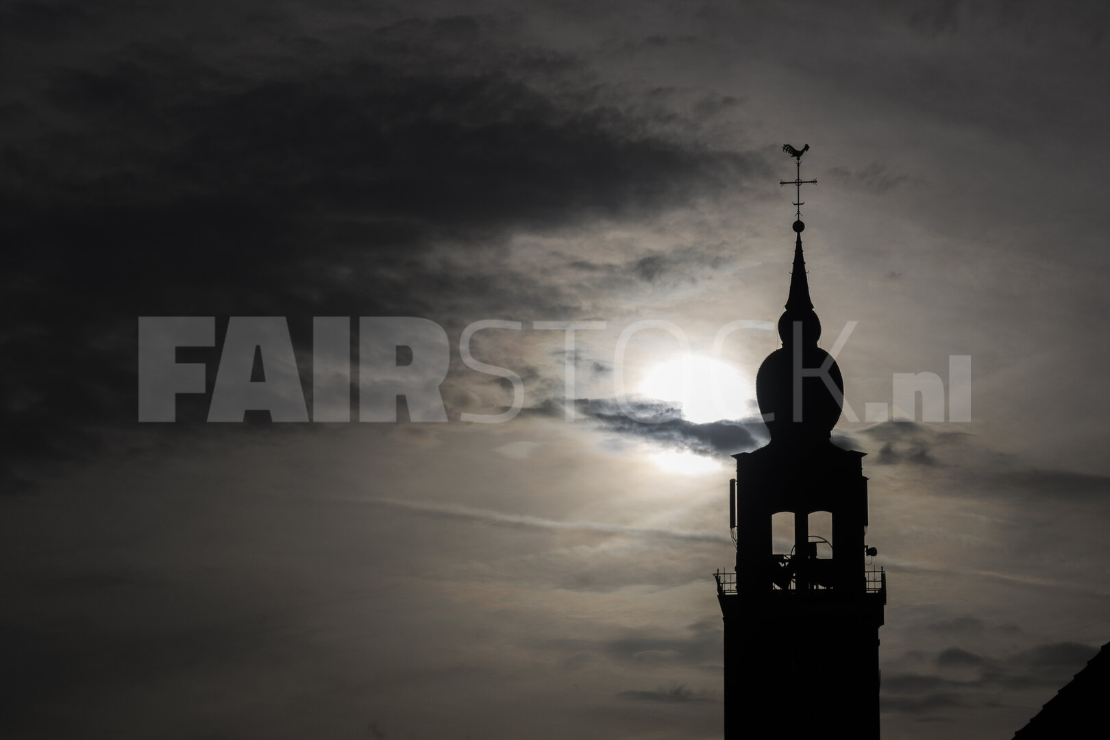 Silhouette of a church tower against a dramatic sky in Noord-Bra