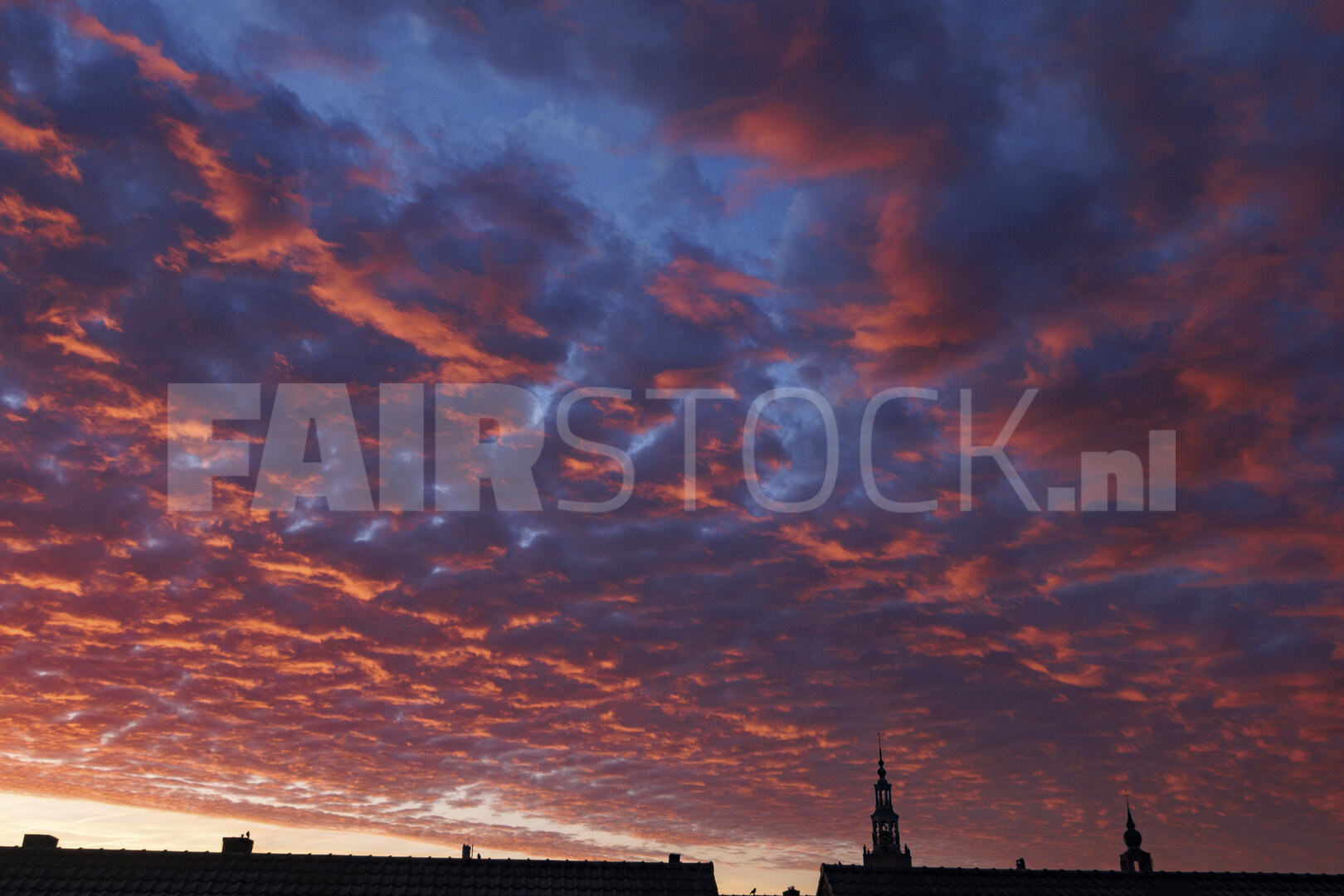 Dramatische zonsondergang boven daklijnen