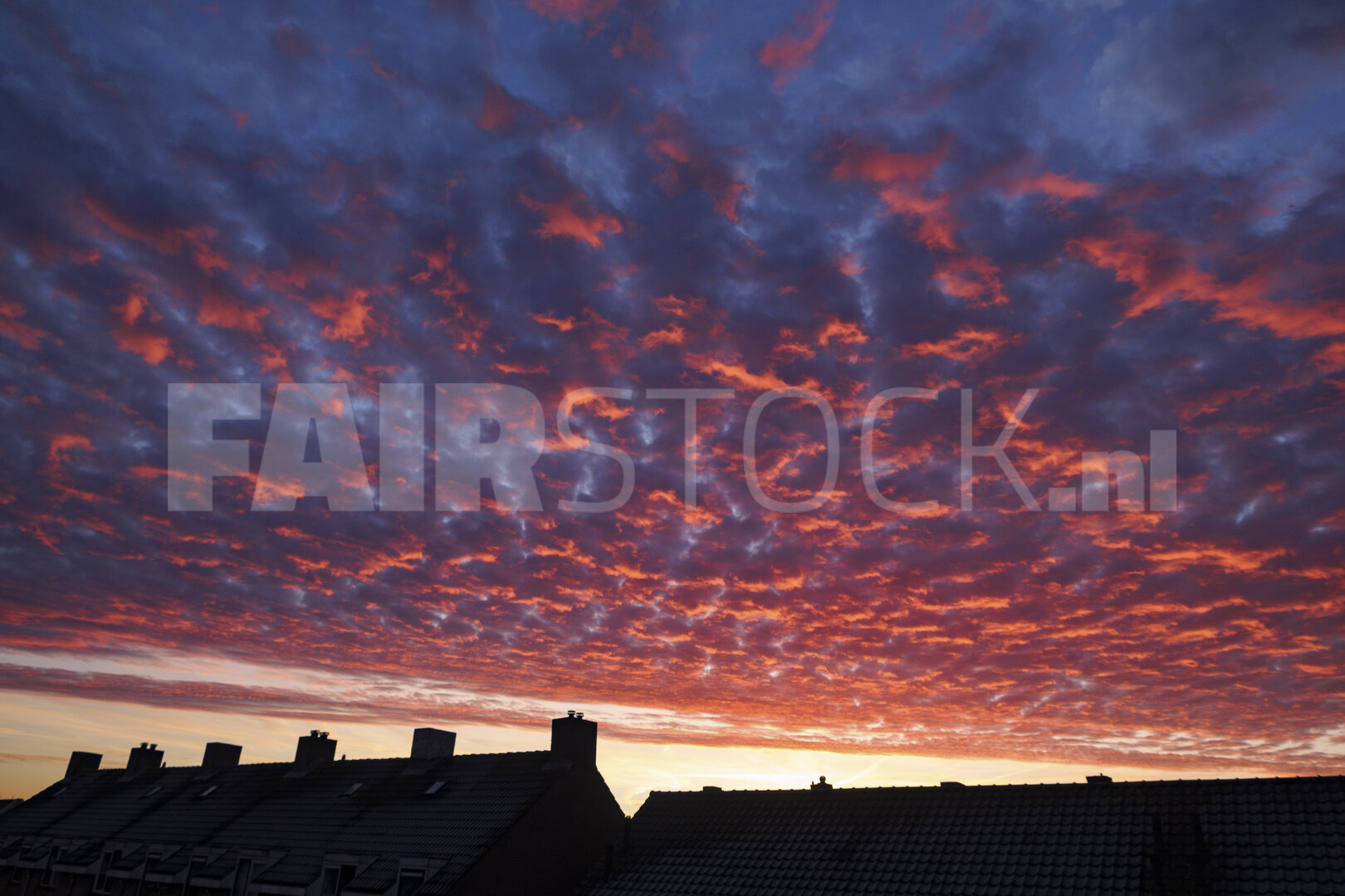 Kleurrijke zonsondergang boven daken