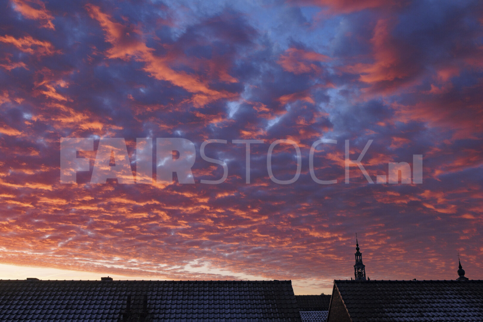 Vibrant sunset casts colorful hues over rooftops in a tranquil e