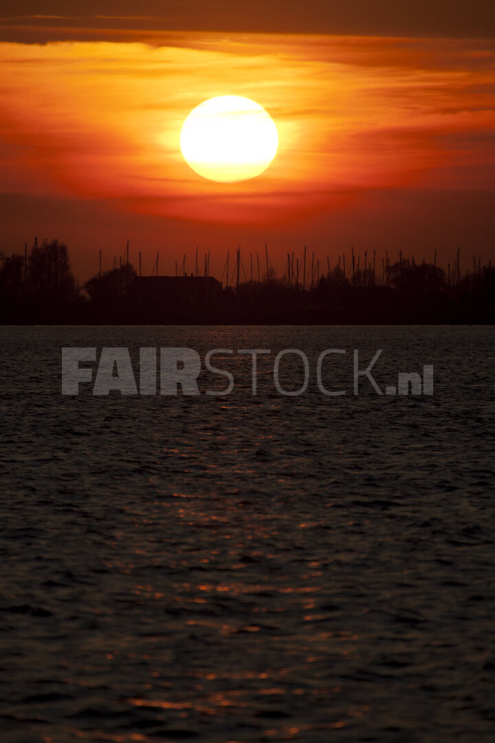 Levendige rode zonsondergang boven brede rivier