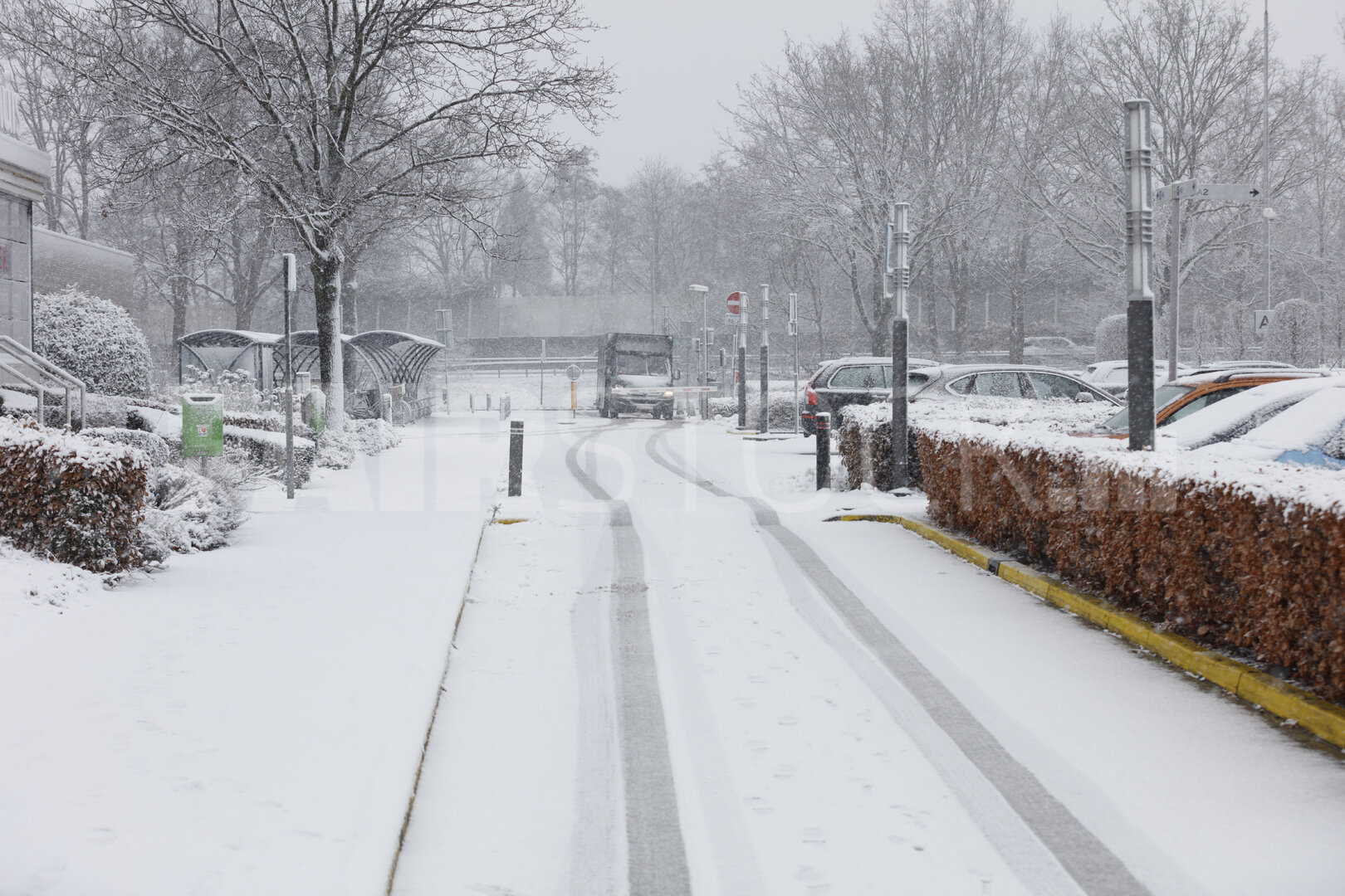 Besneeuwde straat met geparkeerde auto's en busbaan