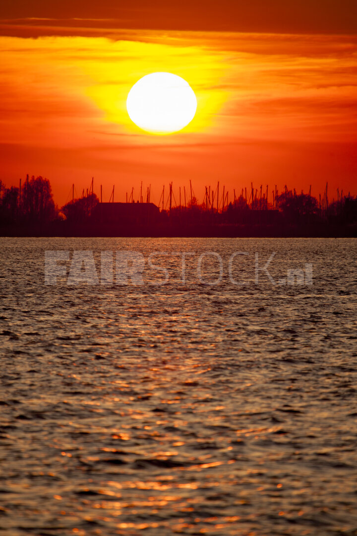 Levendige rode zonsondergang boven brede rivier