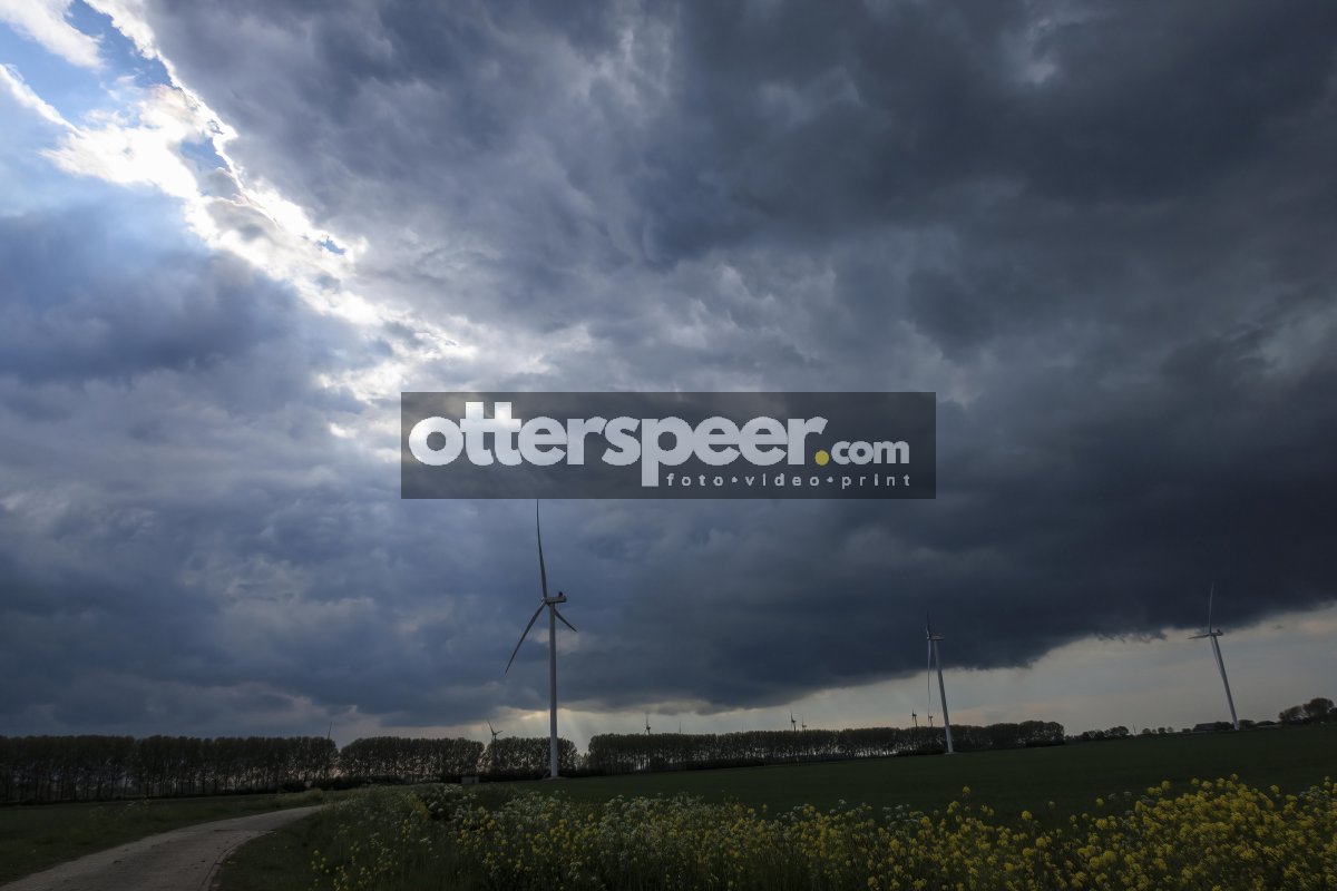 Dark clouds gather over a wind farm in a rural landscape during